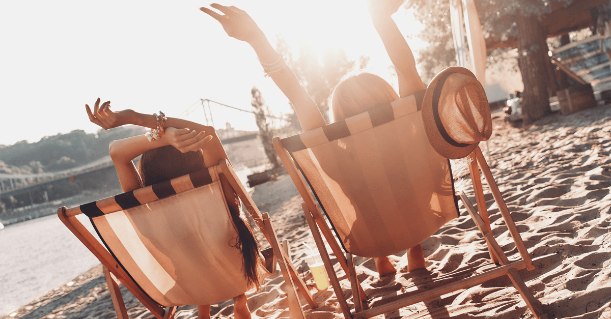 Two people sitting in deck chairs on a beach